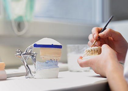 A denturist adding the finishing touches to a new denture