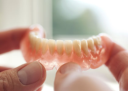 A denturist holding a new lower denture